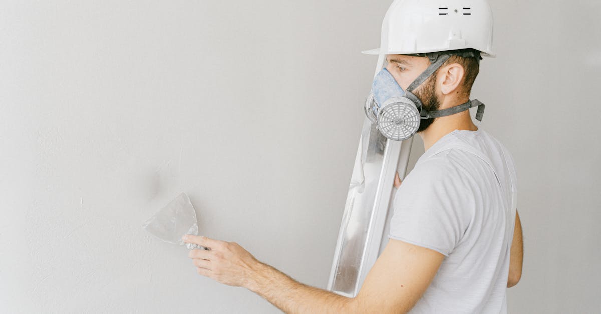 pexels-photo-5493652-5493652 Man in White T-shirt Wearing White Gas Mask Using Flat Metal Spatula on the Wall